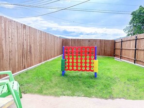 A backyard with a wooden fence, a colorful play structure, and a green plastic chair.