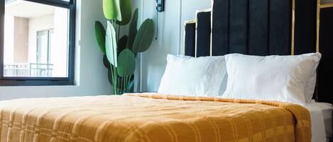A hotel room with a bed, a window, and a plant.