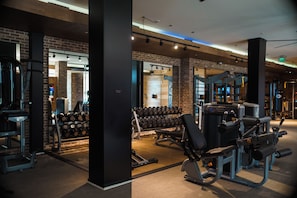 Une salle de sport équipée de divers appareils d’exercice, notamment des haltères et des machines de musculation.