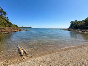 Una vista clara d'una platja de roques amb aigua tranquil·la i paisatges llunyans.