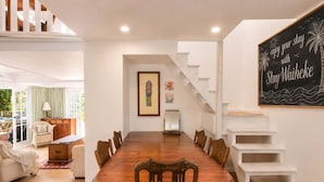 Un comedor con una mesa y sillas de madera, una escalera y un cuadro en la pared.