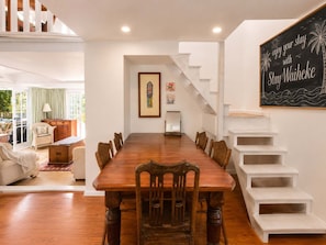 Uma área de refeições com uma mesa e cadeiras de madeira, uma escada e um quadro na parede.
