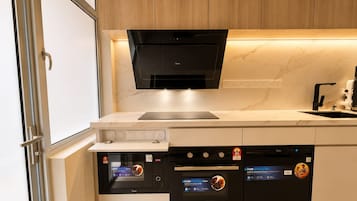 A modern kitchen with built-in appliances, including a microwave, oven, and dishwasher, under a sleek black hood.
