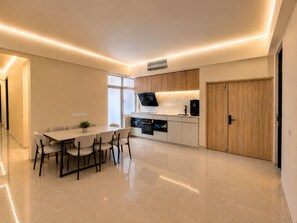 A modern kitchen with a dining area, built-in appliances, and a wooden door. - Central Georgetown Homestay for 8 Pax . Chulia Street, Penang (George Town)