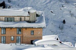 Un hôtel à la façade en bois, sur laquelle on peut lire l’inscription « HÔTEL WONDSCHEIN ».