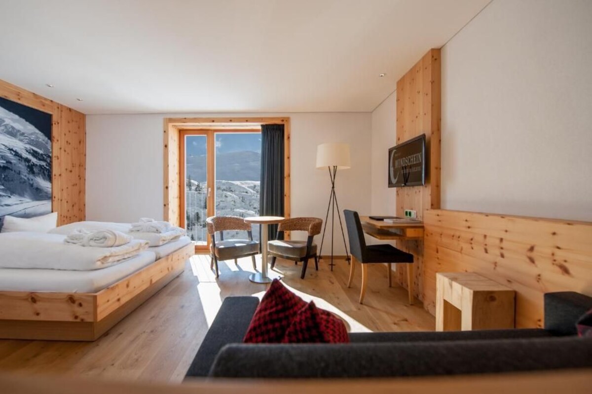 Une chambre d’hôtel avec un lit, un bureau, une chaise, un canapé et une vue sur les montagnes.