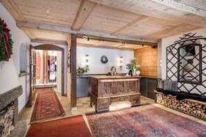 Un espace d’accueil comprenant un comptoir de réception en bois, une cheminée et un mur décoratif.