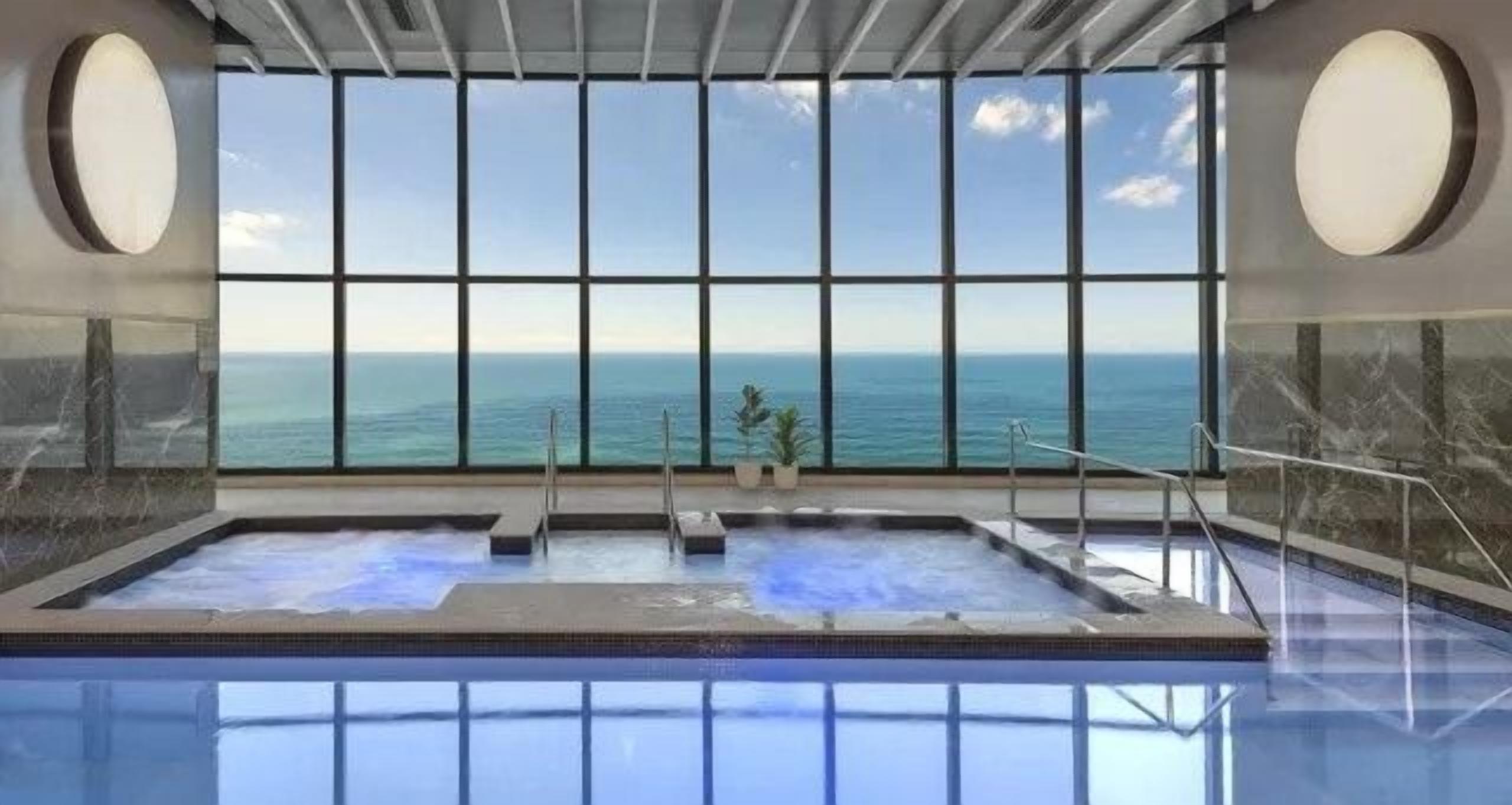 Une piscine intérieure avec vue sur l’océan, grâce à de grandes fenêtres.