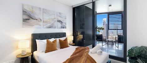 Habitación de hotel moderna con una cama grande, vistas a la ciudad y un balcón con una planta.