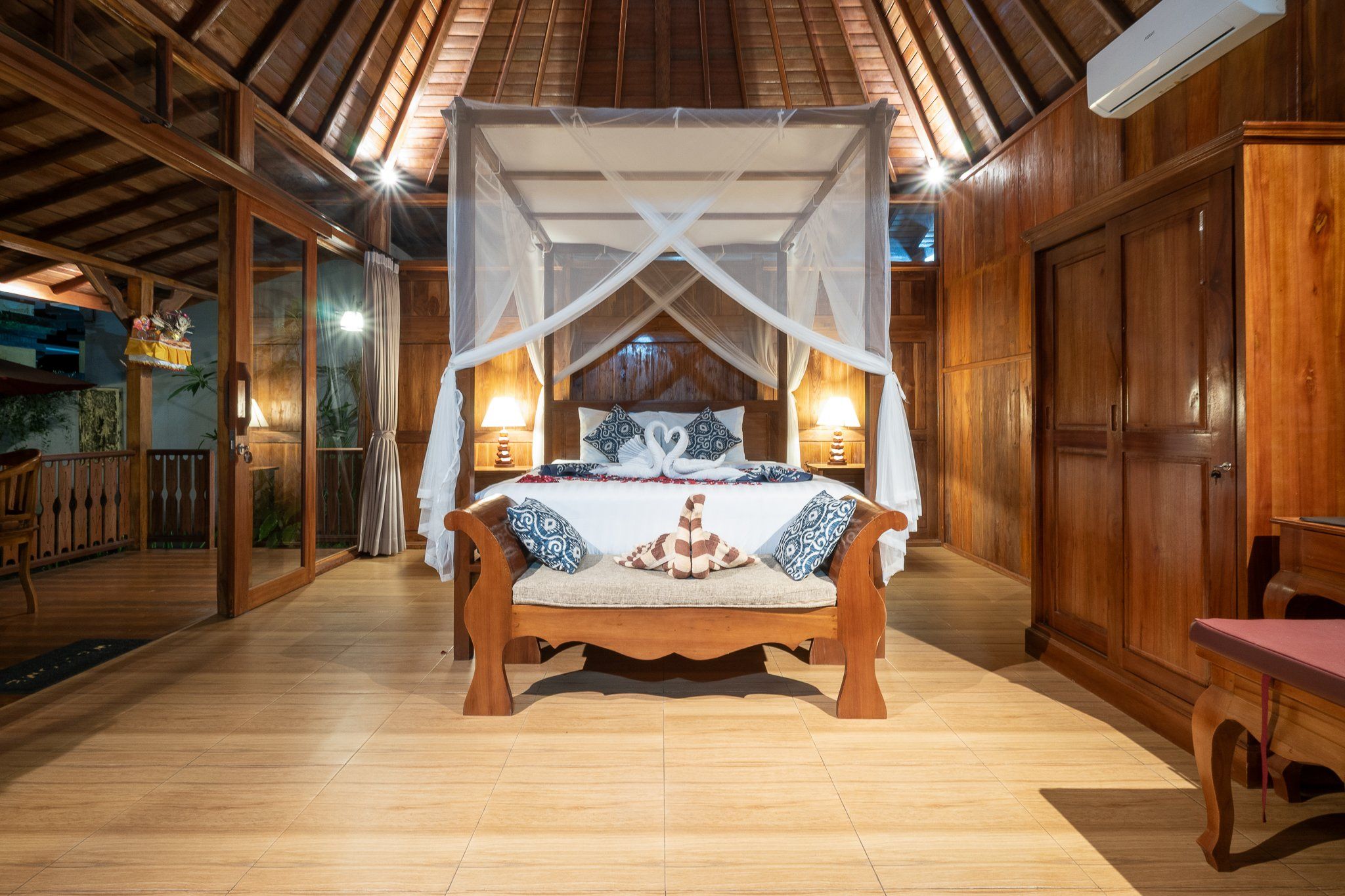 A wooden room with a bed under a canopy, wooden floors, and a wooden door.