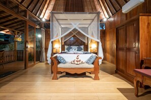 A wooden room with a bed under a canopy, wooden floors, and a wooden door.