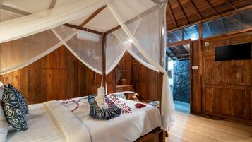 A bedroom with a canopy bed, wooden walls, a stone wall view, and a television.