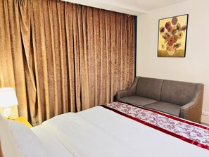 Ein Hotelzimmer mit Bett, Sofa, Vorhang und einem Bild an der Wand.