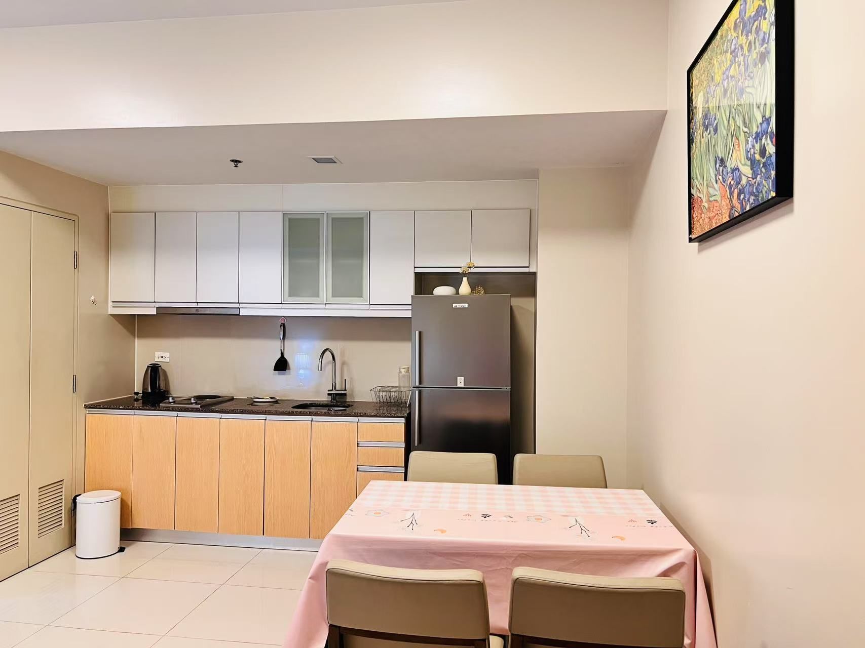 A compact kitchen with a dining area, featuring a refrigerator, stove, sink, and a table with chairs.