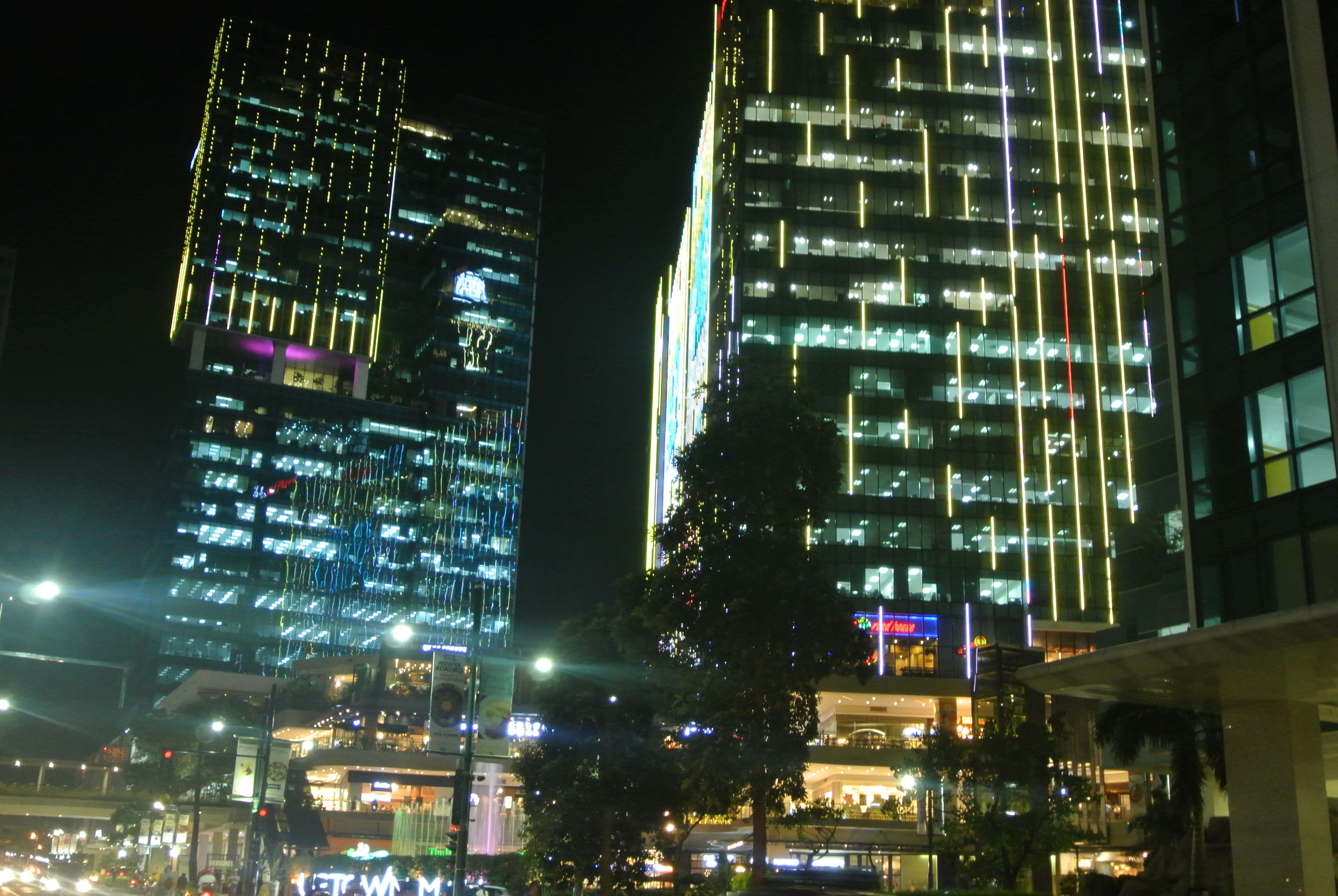 A nighttime cityscape with illuminated skyscrapers and a Christmas tree.
