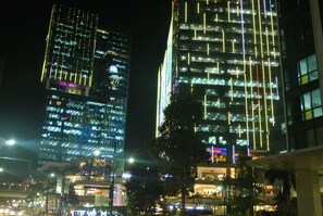 A nighttime cityscape with illuminated skyscrapers and a Christmas tree. - One Uptown Residence BGC Work & Unwind | Heart of BGC (Makati City)