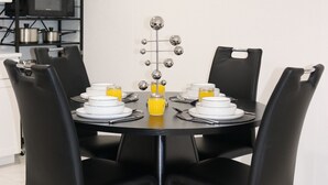 A dining area with a round table, black chairs, and a wall-mounted clock. - Harmony Luxe at Sarasota (Sarasota)