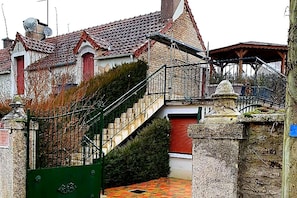 Ein traditionelles Steinhaus mit rotem Ziegeldach, einer Treppe, die zu einem zweiten Stock führt, und einem verschlossenen Eingang.