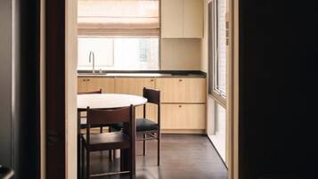 A narrow hallway leading to a kitchen with a dining table and chairs.