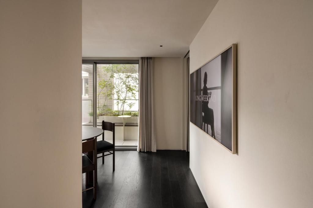 A modern interior with a dining area, a large window, and a framed artwork on the wall.