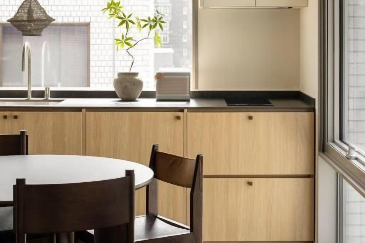 Una cocina moderna con una mesa de comedor y sillas, una planta en maceta y una ventana con persianas.