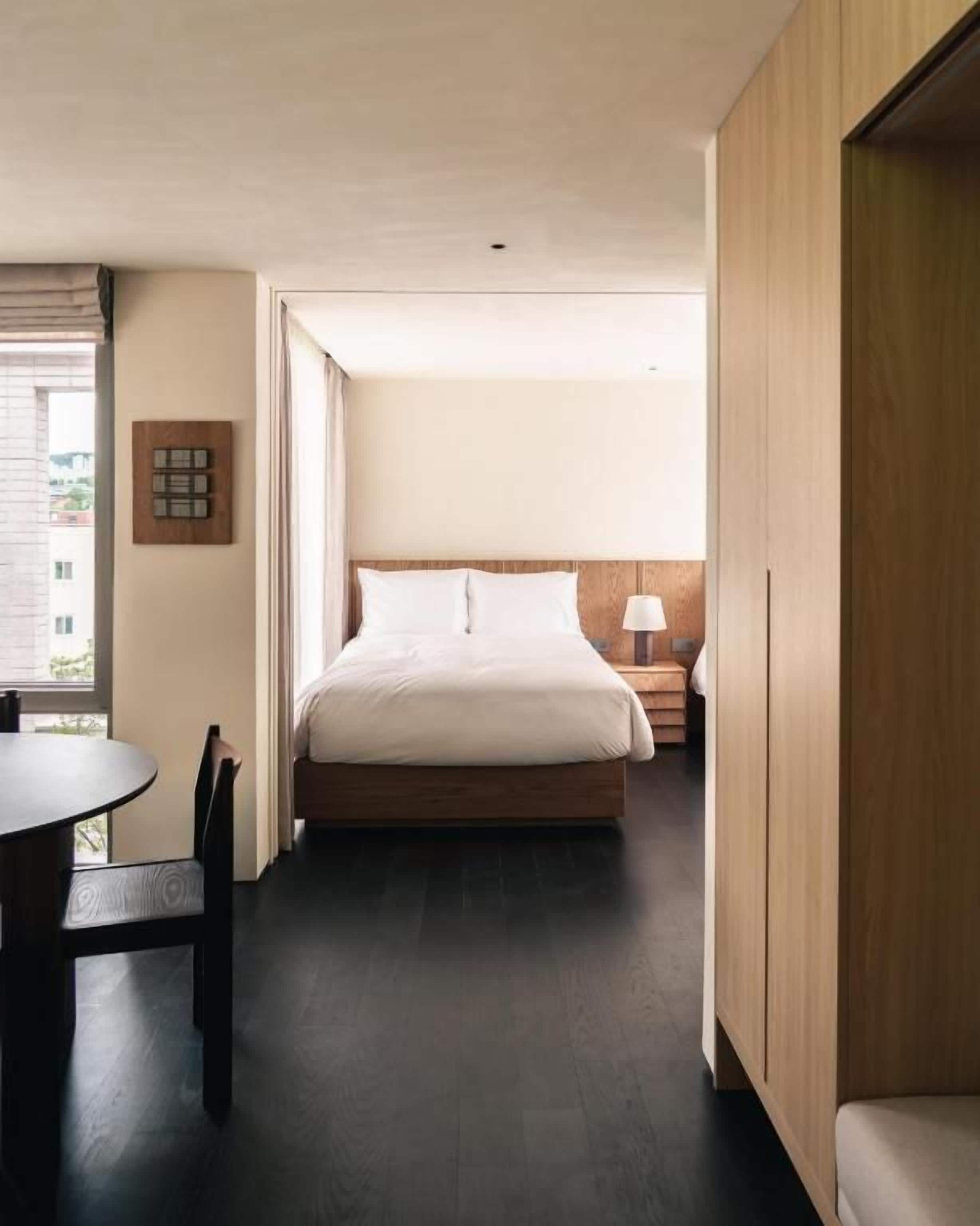 Un dormitorio con cama, mesita de noche y ventana.