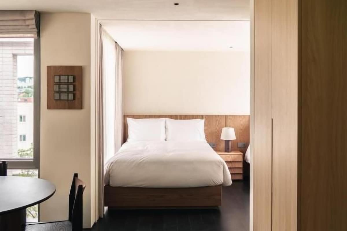 Quarto com cama, mesa de cabeceira e janela.