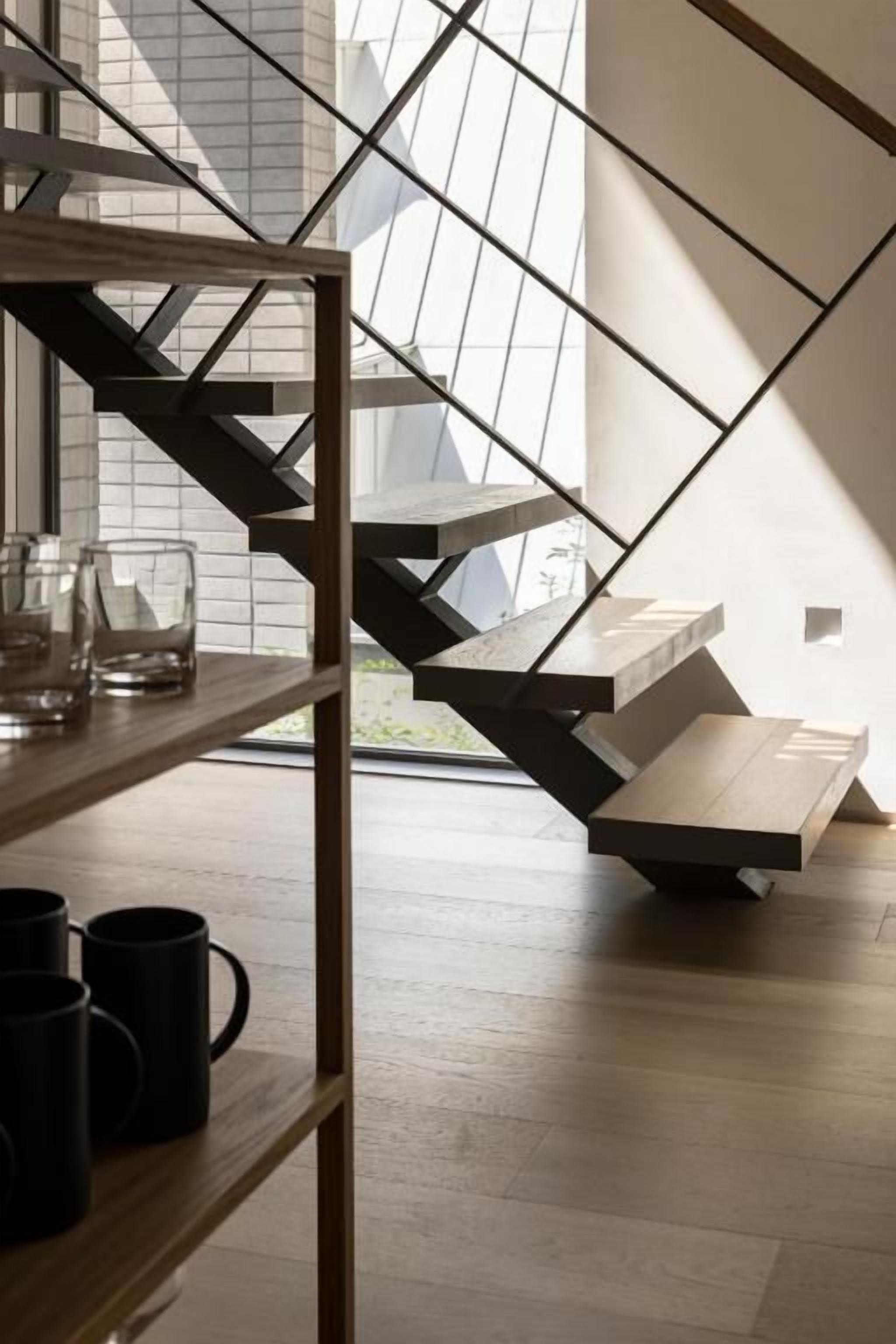 A modern staircase with a geometric design, leading to a landing area with a white surface.