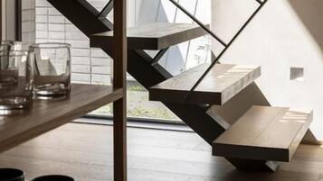 A modern staircase with a geometric design, leading to a landing area with a white surface.