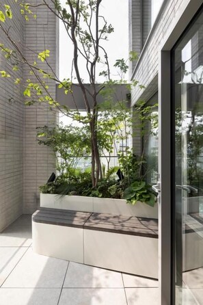 Un edificio moderno con entrada de vidrio, piso de baldosas y un jardín vertical con plantas.