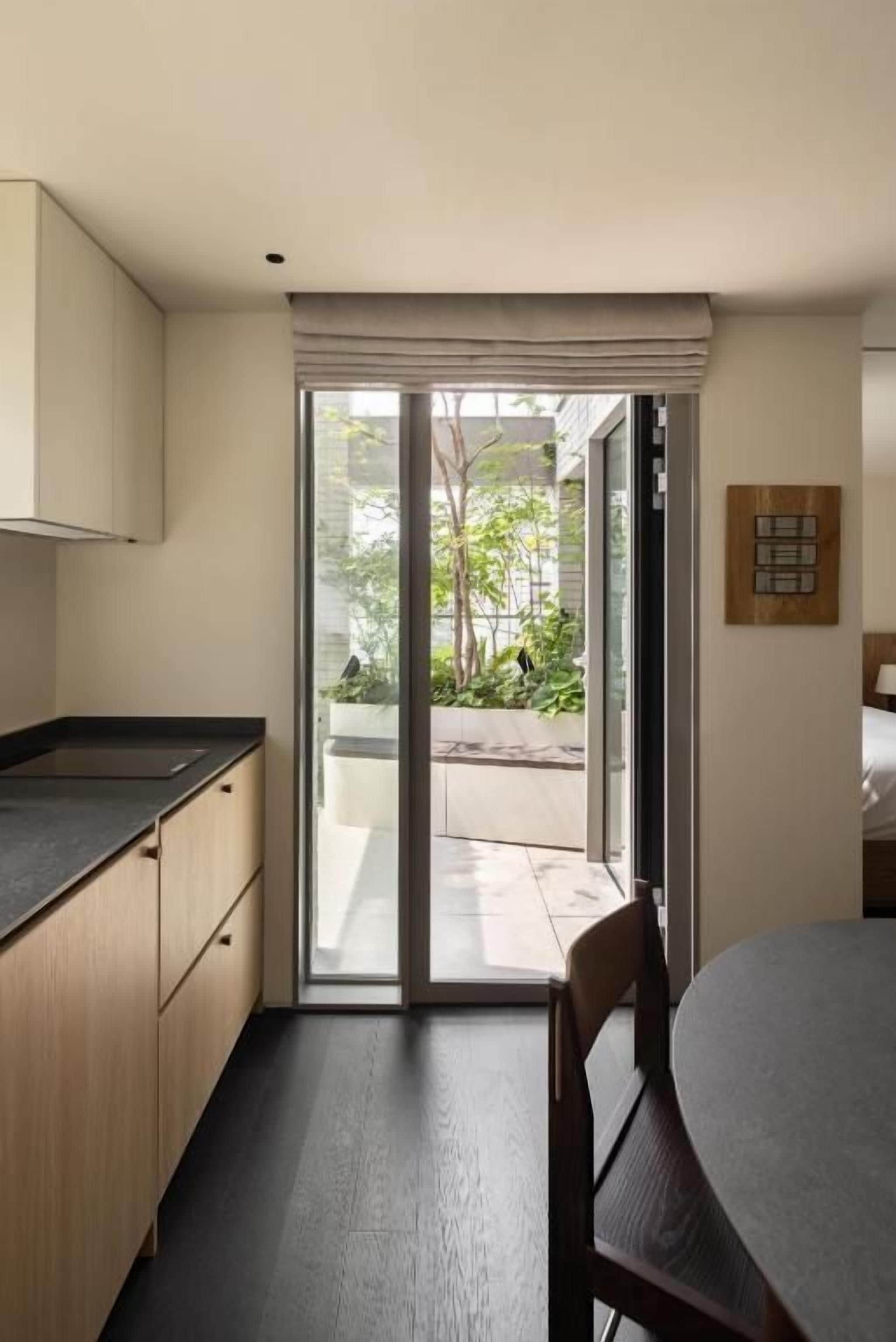 A modern kitchen with a dining area, a sliding glass door leading to an outdoor space, and a wooden cabinet.