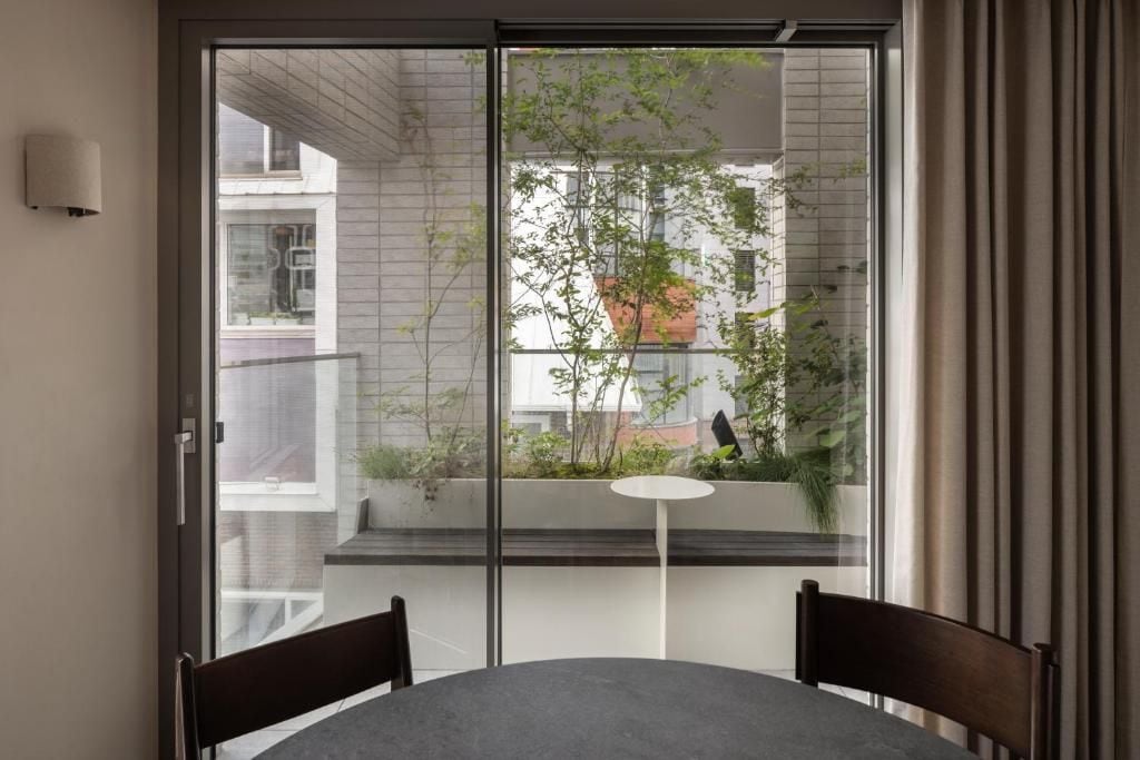 A room with a sliding glass door leading to a balcony, a round table, and two chairs.