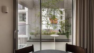 A room with a sliding glass door leading to a balcony, a round table, and two chairs.