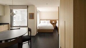Una habitación de hotel con cama, mesita de noche y ventana con persianas.
