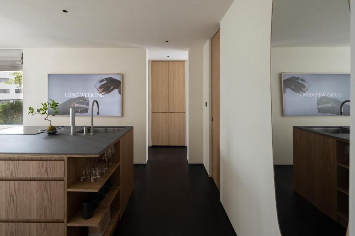 Una cocina moderna con una isla central, armarios de madera y encimera negra.