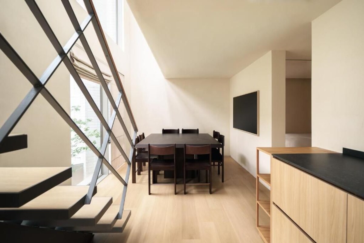 Una cocina moderna con comedor, una escalera y un televisor montado en la pared.