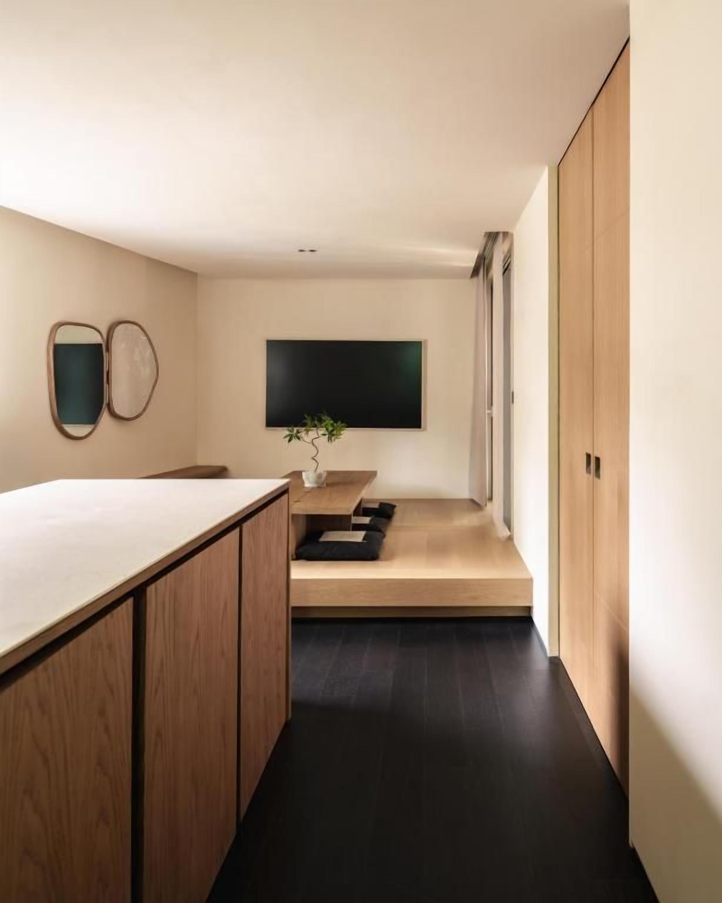 Un interior moderno con una zona de cocina, un espacio para sentarse y un televisor de pantalla plana grande montado en la pared.