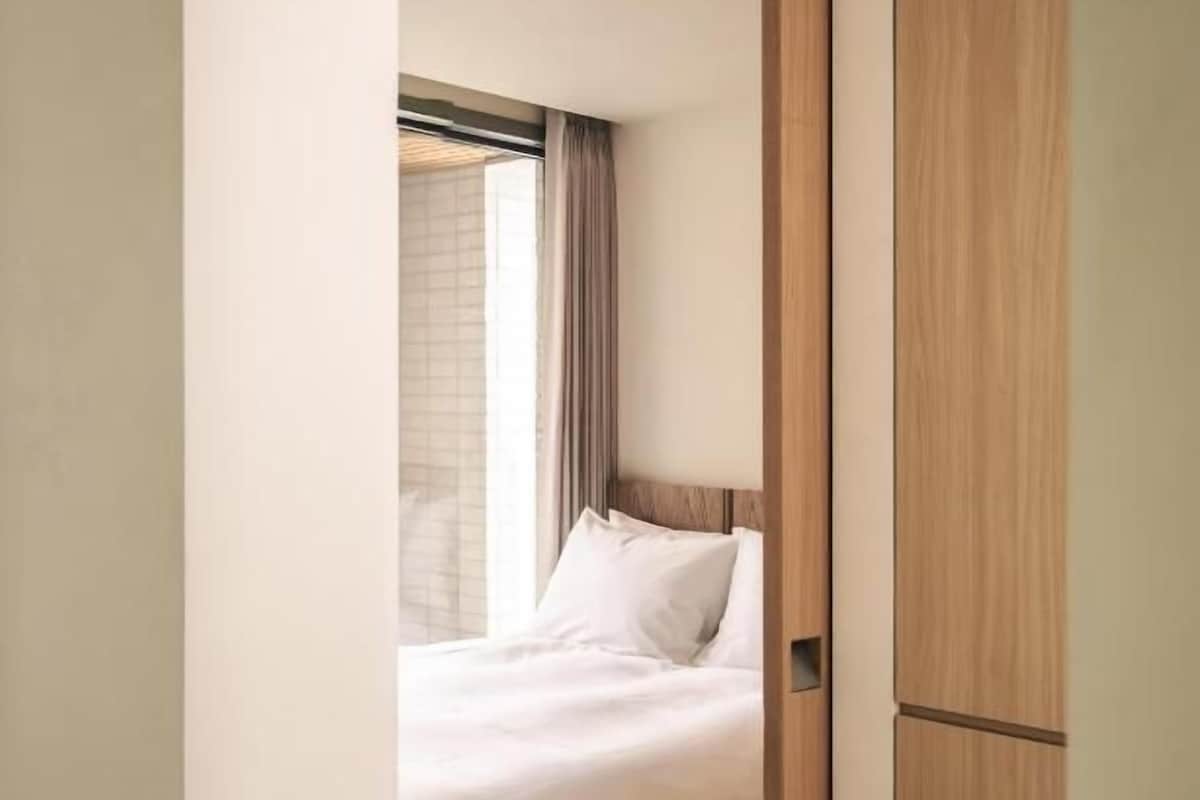 Quarto com cama, janela com cortinas e guarda-roupa de madeira.
