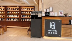 A hotel reception area with a reception desk, a bookshelf with magazines, and a sign indicating the hotel name. - Hub Hotel Chiayi (Chiayi)