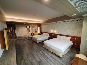Habitación de hotel con dos camas, piso de madera, pared decorativa con motivos geométricos y un escritorio pequeño.