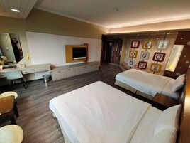 A hotel room with two beds, a desk, a TV, and a wall with decorative elements.