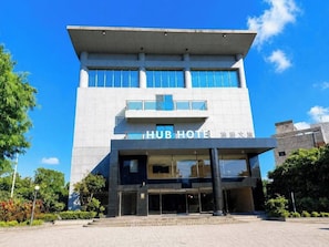 A modern hotel with a prominent entrance, large windows, and a clear sky.