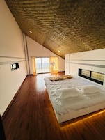 Un dormitorio con techo inclinado, una cama, una ventana con cortinas y un ventilador.