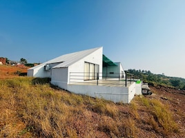 Una casa moderna de color blanco con techo plano, un balcón y vistas a un paisaje montañoso.