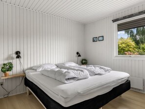 A bedroom with a bed, bedside lamps, a window with a view of trees, and a small plant on a nightstand. - "Efrosina" - 600m from the sea by Interhome (Hejls)