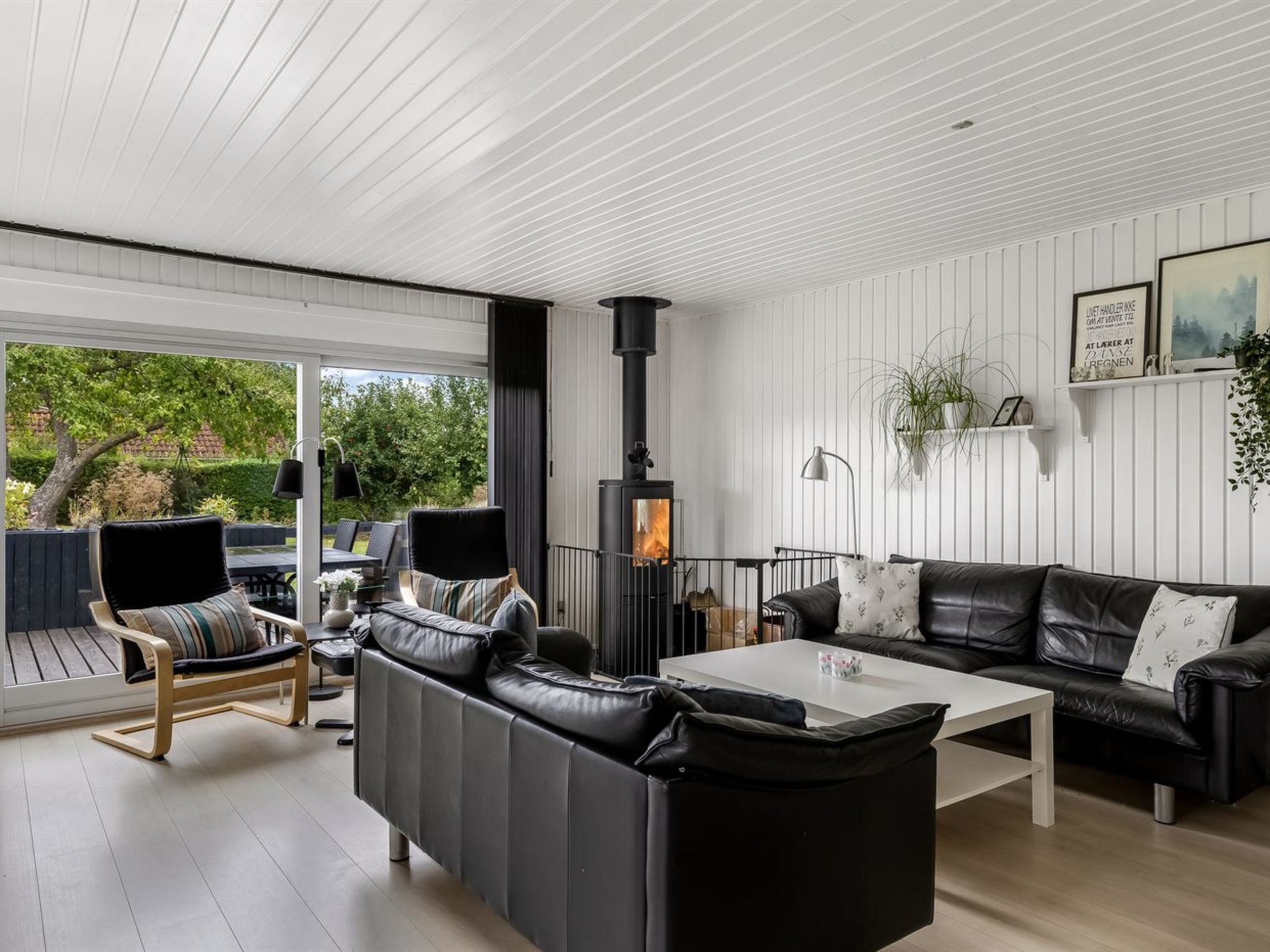 A modern living room with a fireplace, leather sofas, a coffee table, and a view of the outdoors.