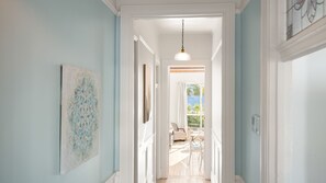 A hallway with a light blue wall, a hanging pendant light, and a door leading to a room with a view of the outdoors. - Cascade Canopy Katoomba Mountain Minutes from Three Sisters (Katoomba)