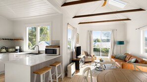 A bright kitchen with a central island, wooden stools, a dining area with a table and chairs, and a living room with a sofa and a lamp. - Cascade Canopy Katoomba Mountain Minutes from Three Sisters (Katoomba)