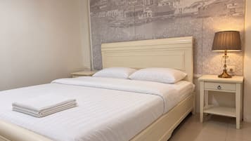 A hotel room with a bed, a nightstand with a lamp, and a wall mural.