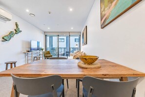 A modern dining area with a wooden table, two grey chairs, and a decorative bowl. - Christchurch CBD - 2BR with Parking & Balcony (Christchurch)